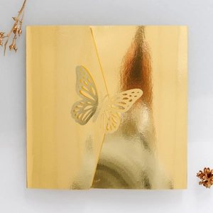 Macro view of a square gold mirror finish invitation cover with 3D laser-cut butterfly detail