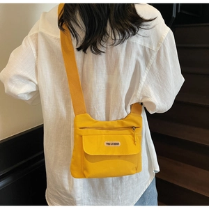 Vista posteriore della modella con borsa a tracolla in nylon giallo e cinghia larga