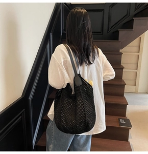 Gros plan d'un sac cabas en maille noire avec texture tissée et bandoulière en cuir