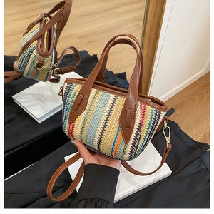 Détail d'un sac seau tressé coloré avec des poignées en cuir marron et une bandoulière