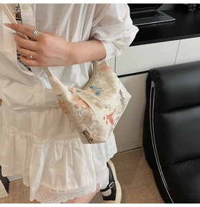 Detailed embroidery of butterflies and floral patterns on cream-white canvas hobo bag