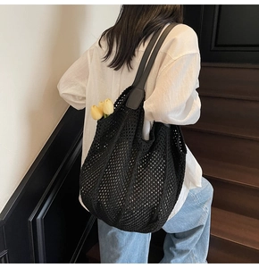 Détail d'un sac cabas en crochet noir avec des bretelles en cuir portées sur l'épaule