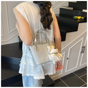 Silberne Pailletten-Eimertasche mit weißem Plüsch-Anhänger und glänzenden Spiegelgriffen