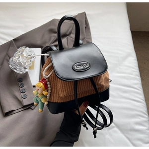 Detailansicht des Rucksacks aus Leder und Stroh-Patchwork mit Metalllogo und Anhänger