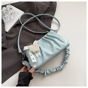 Detail of light blue pleated bag with pearl heart charm and lace bow decoration