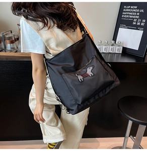 Detail of black nylon crossbody bag with sequined dachshund patch in a cafe setting
