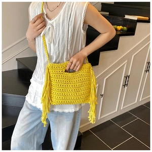 Detailed view of yellow hand-crocheted knit bag texture and decorative fringe tassels