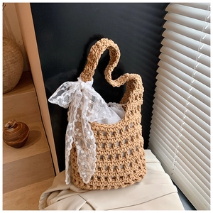 Detail der geflochtenen Strohtasche mit weißer Spitzenschleife und Innenbeutel