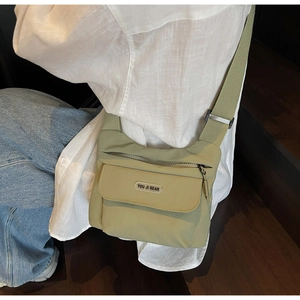 Dettaglio della borsa a tracolla in tela verde chiaro con tracolla regolabile e patch