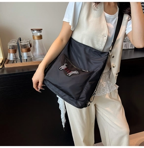 Detail of black nylon crossbody bag featuring cute puppy rhinestone patch and zipper pocket