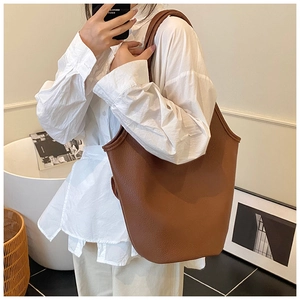 Deep brown pebbled leather tote bag with wide shoulder strap shown on a model