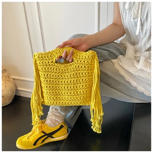Detailed view of handmade yellow knit handbag with stylish tassel accents and woven texture