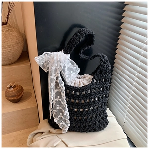Detail of hand-woven black straw bucket bag with lace bow and drawstring pouch