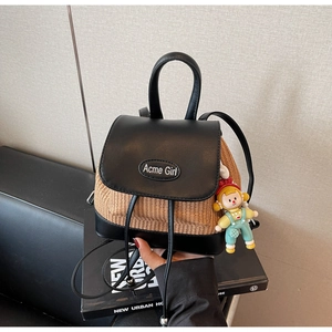Detailansicht des gewebten Stroh-Rucksacks mit schwarzem Leder und Acme Girl Logo-Tag