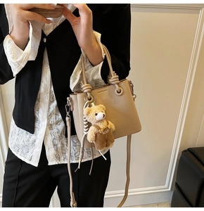 Detail view of apricot lychee pattern bucket bag with a cute bear plush pendant