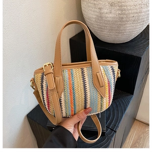 Détail du sac seau en paille tissée colorée avec anse en cuir marron et boucles dorées
