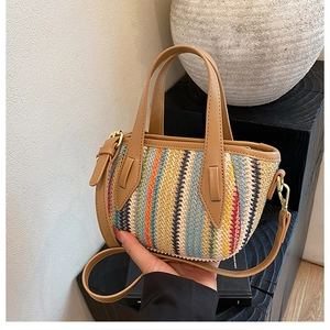 Détail du sac seau en paille tissé à rayures colorées avec anse en cuir marron et boucle or