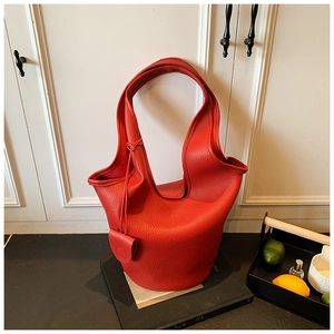 Close-up of red lychee leather bucket bag with thick round base and side tags