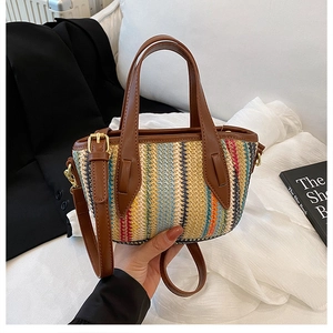 Détail d'un sac seau en paille tissée colorée avec poignées en cuir brun et bandoulière
