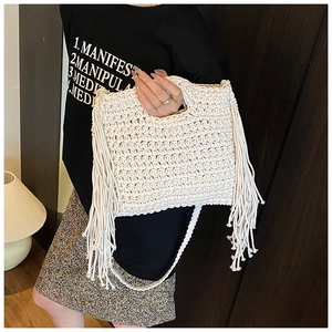 Detail of bohemian knit handbag featuring dense side tassels and woven shoulder strap