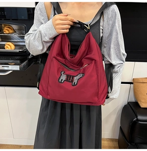 Detail of burgundy tote bag with cute cartoon dog embroidery patch and zipper pocket