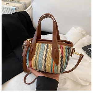 Détail du sac seau en paille tissée colorée avec poignées en cuir marron et boucles dorées