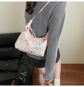 Detail of pink embroidered canvas bag with floral and butterfly patterns and beaded cord
