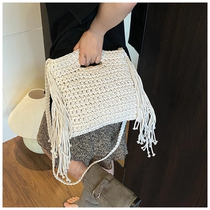 Detailed shot of white knit crossbody bag with long tassels on a casual model outfit