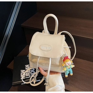 Nahaufnahme des Mini-Rucksacks aus Stroh und Leder mit Logo und blauem Anhänger