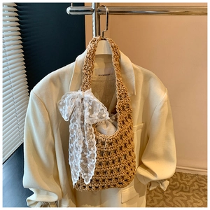 Detail of hand-woven straw bucket bag with large white lace bow and drawstring pouch