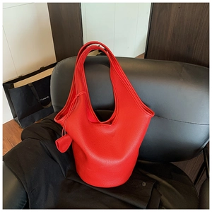 Detail of red lychee grain leather bucket bag with top handle and side leather charm