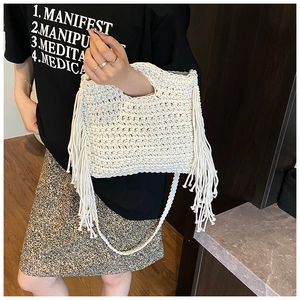 Detail of hand-woven cream knit bag featuring long side tassels and bohemian shoulder strap