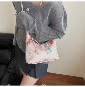 Detail of pink embroidered canvas bag with goldfish pattern and pearl drawstring closure