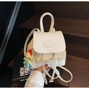 Detail eines cremefarbenen Rucksacks mit Strohstruktur, Kunstleder und Perlen-Accessoire