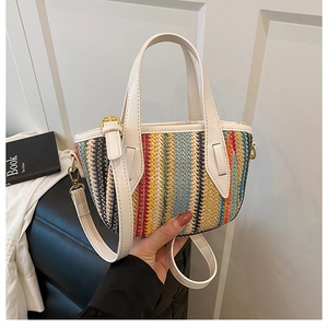 Détail du sac seau en paille tissée avec rayures multicolores et poignées en cuir