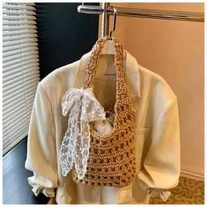Detail of woven straw bucket bag with white lace bow and drawstring inner lining