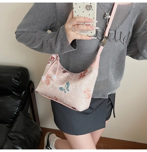 Detail of embroidered hobo bag with traditional butterfly and cloud patterns on silk fabric