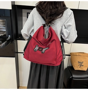 Detail of red nylon backpack featuring sequined dachshund puppy embroidery and adjustable straps