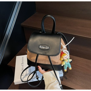Detail eines gewebten Eimer-Rucksacks mit Lederbesatz und Cartoon-Perlenanhänger auf Holztreppe