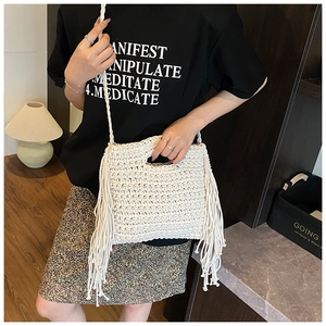 Detail of a beige woven crossbody bag with long fringes and a bohemian knit texture