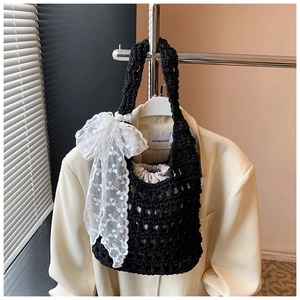 Detail of black crochet bucket bag featuring a large white lace bow and fabric drawstring