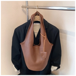 Close-up of brown pebbled leather bucket bag hanging on a suit hanger for display