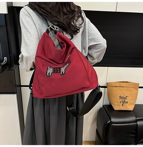 Detailed view of a red nylon crossbody bag featuring a striped dachshund patch and gold hardware