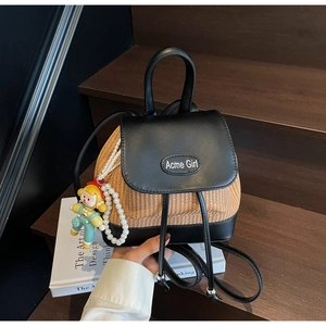 Detail des Mini-Rucksacks aus Stroh und Leder mit Perlenriemen und süßem Puppenanhänger