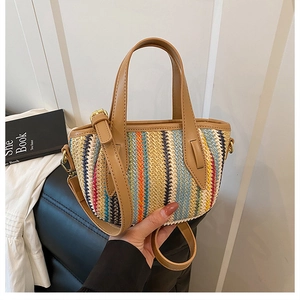 Détail du sac seau en paille tissée colorée avec poignées en similicuir brun et ferrures dorées