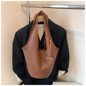 Close-up of brown litchi grain leather bucket bag with matching pendant accessory