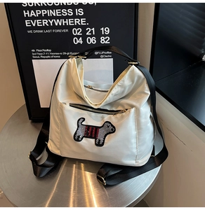 Detail of white nylon tote bag with black dog embroidery on a modern metal table