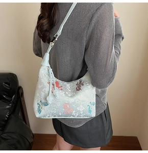 Detail of light blue embroidered hobo bag with butterfly patterns and pearl drawstrings