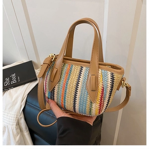 Détail d'un sac seau en paille tissée avec rayures multicolores et anse en cuir brun