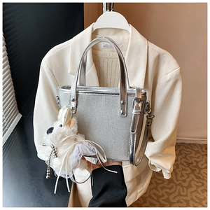 Detail der silbernen Metallic-Tasche mit Netzstruktur und süßem Plüsch-Hundeanhänger